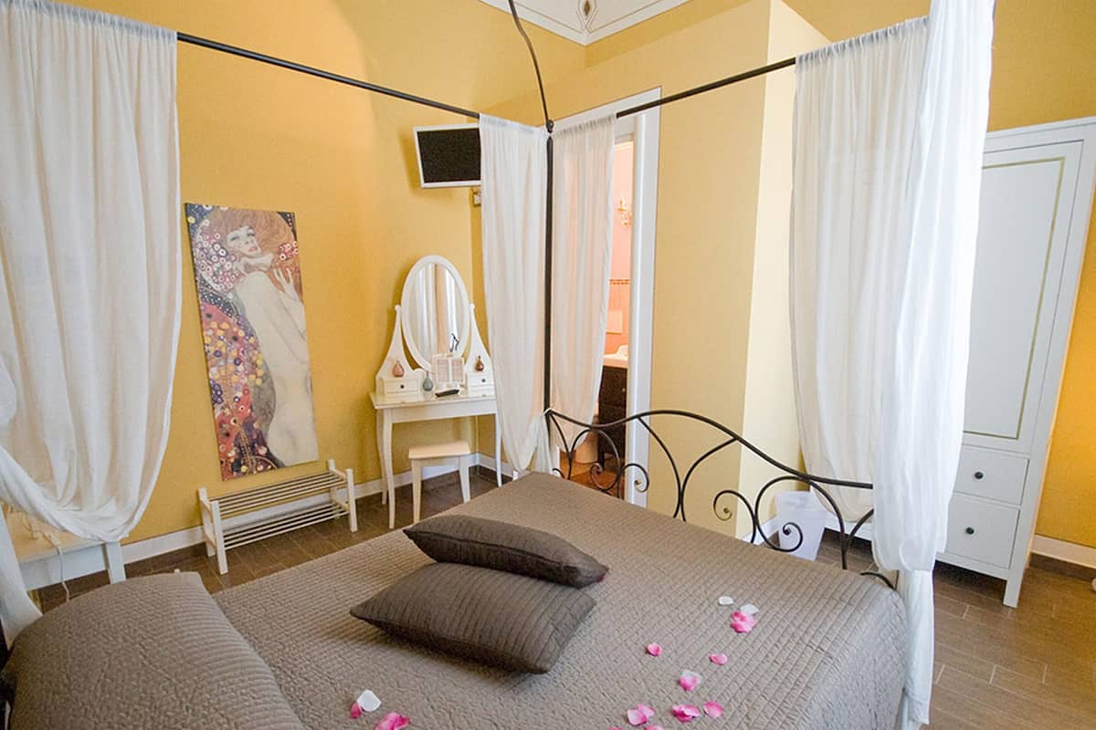A bedroom with a bed, a vanity with a mirror, and a painting on the wall.