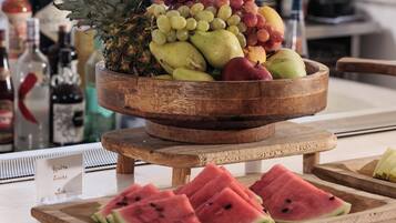 En frugtstander med ananas, druer og vandmelon på et træbord.