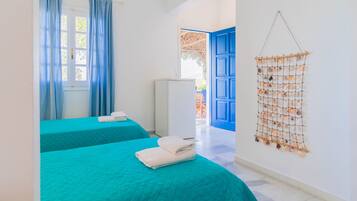 A room with two beds, a hanging light fixture, a wall-mounted decoration, and a door leading to an outdoor area.
