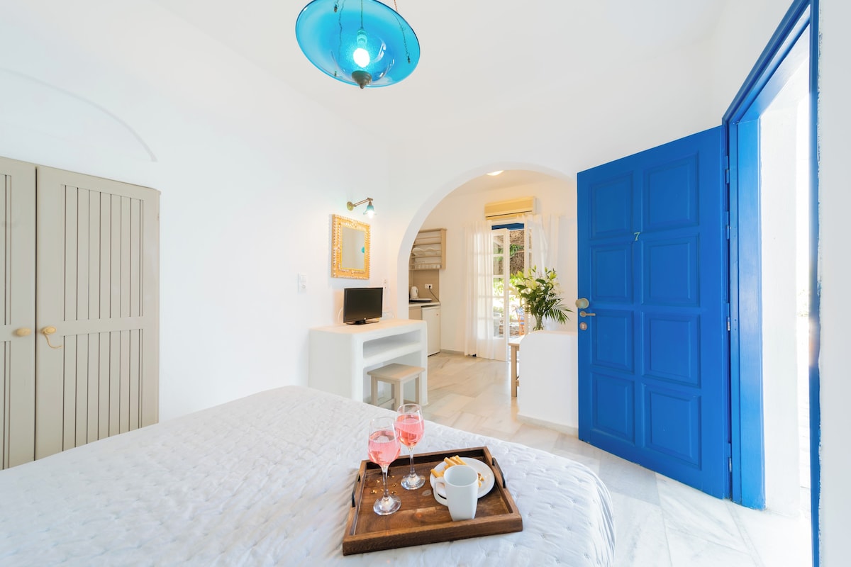 A bedroom with a bed, a tray with snacks and drinks, a TV, and a blue door.