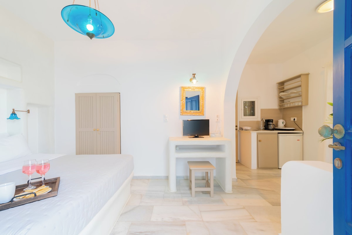 Een moderne hotelkamer met een bed, een zithoekje, een televisie en een kitchenette.