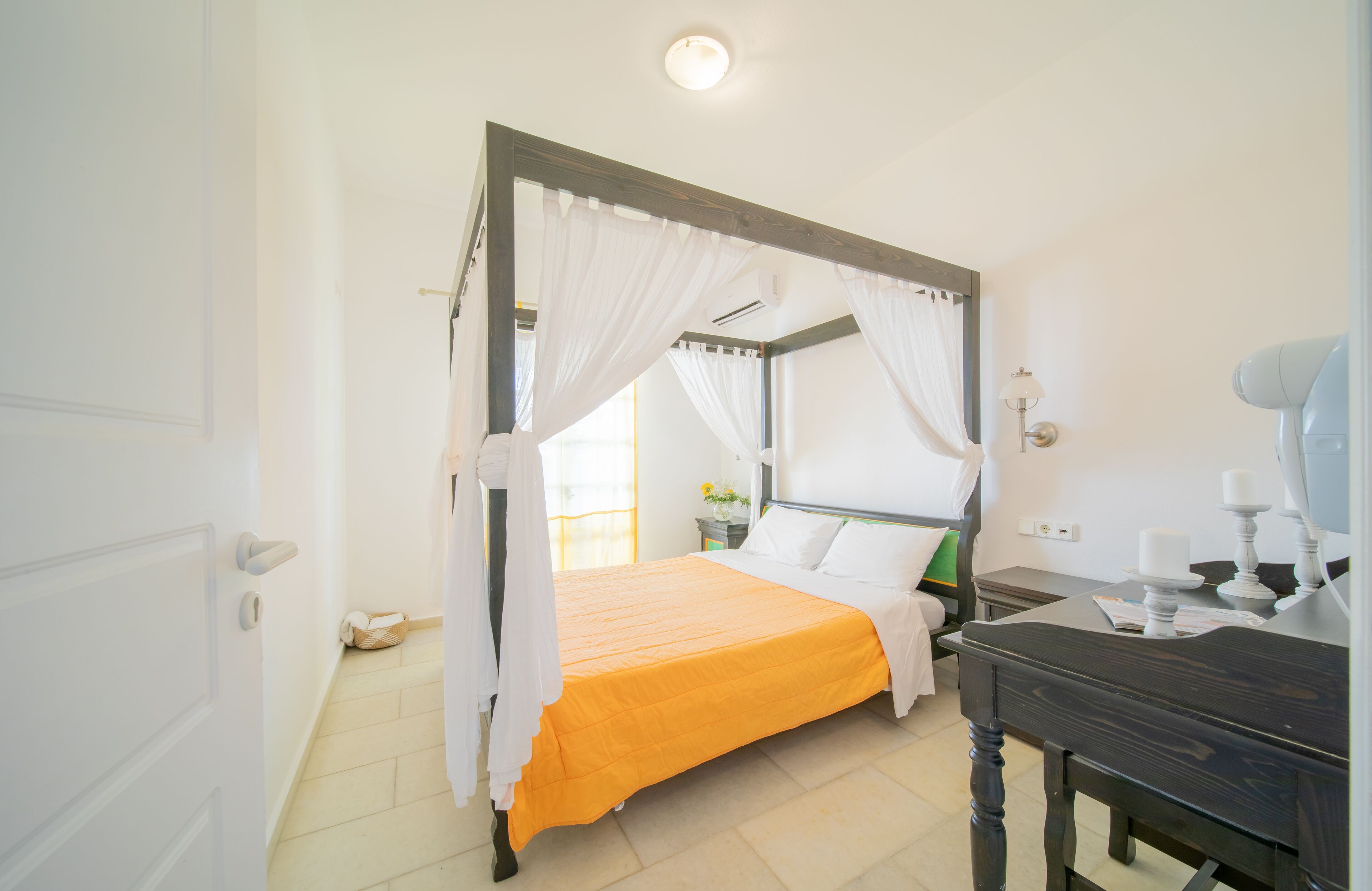 Un dormitorio con cama con dosel, una mesita de noche y una lámpara.