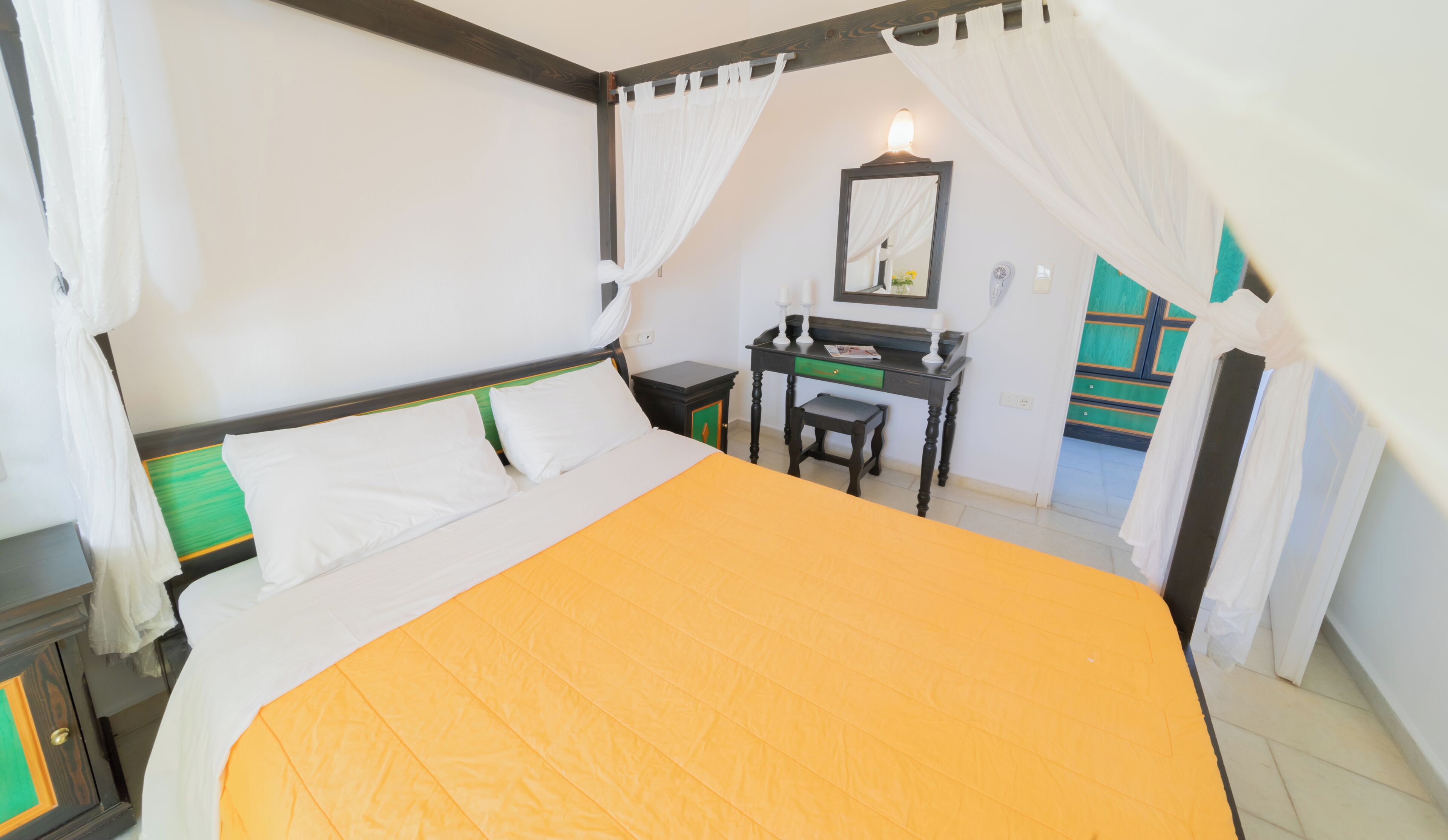 Quarto com cama, escrivaninha, cadeira e espelho.