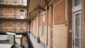 A corridor with a tiled floor, a metal railing, and a door with a brass handle. - Katona Apartments (Budapest)