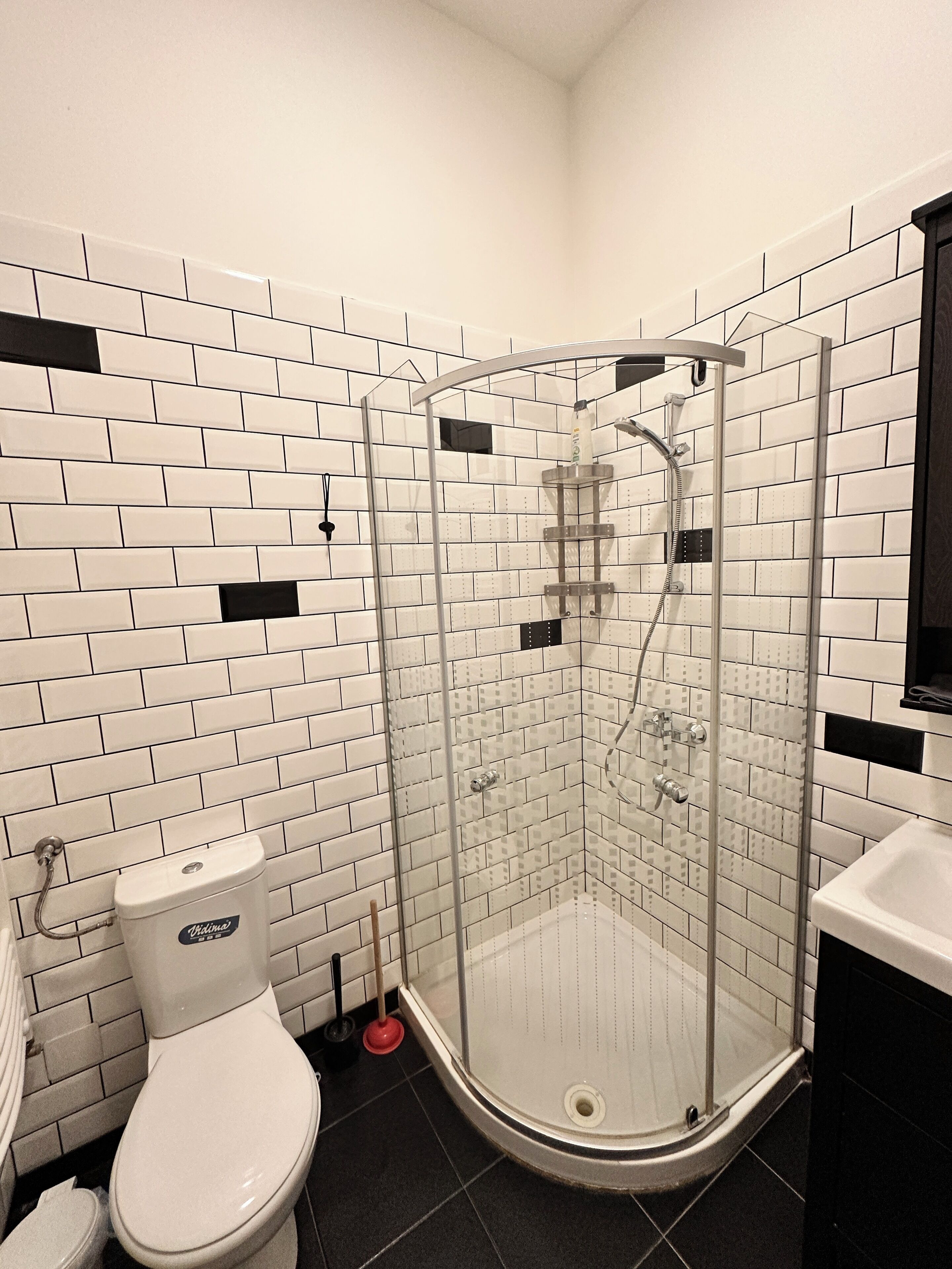 A bathroom with a glass-enclosed shower, a toilet, and a sink.