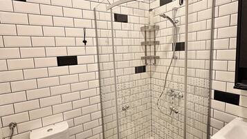A bathroom with a glass-enclosed shower, a toilet, and a sink.