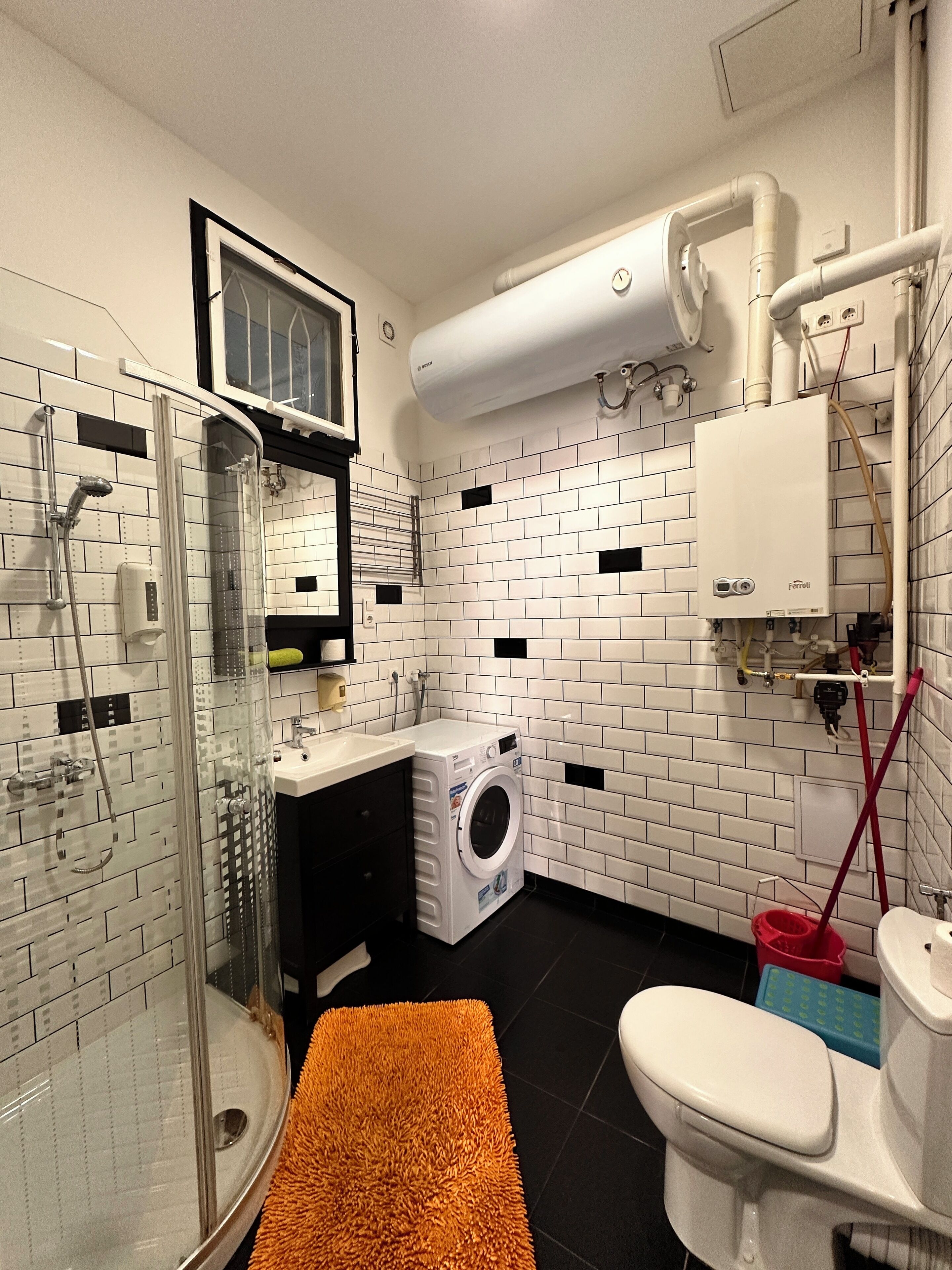 Un bagno moderno con box doccia in vetro, lavatrice e servizi igienici.