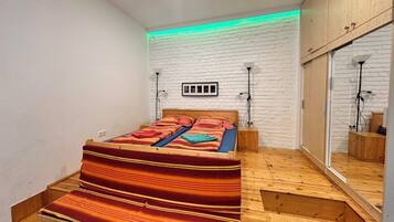 Een slaapkamer met een houten bed, een witte baksteenmuur en een spiegelkast.