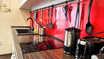 Une cuisine avec un mur de crédence rouge, des appareils électroménagers en acier inoxydable et des ustensiles de cuisine accrochés au mur.