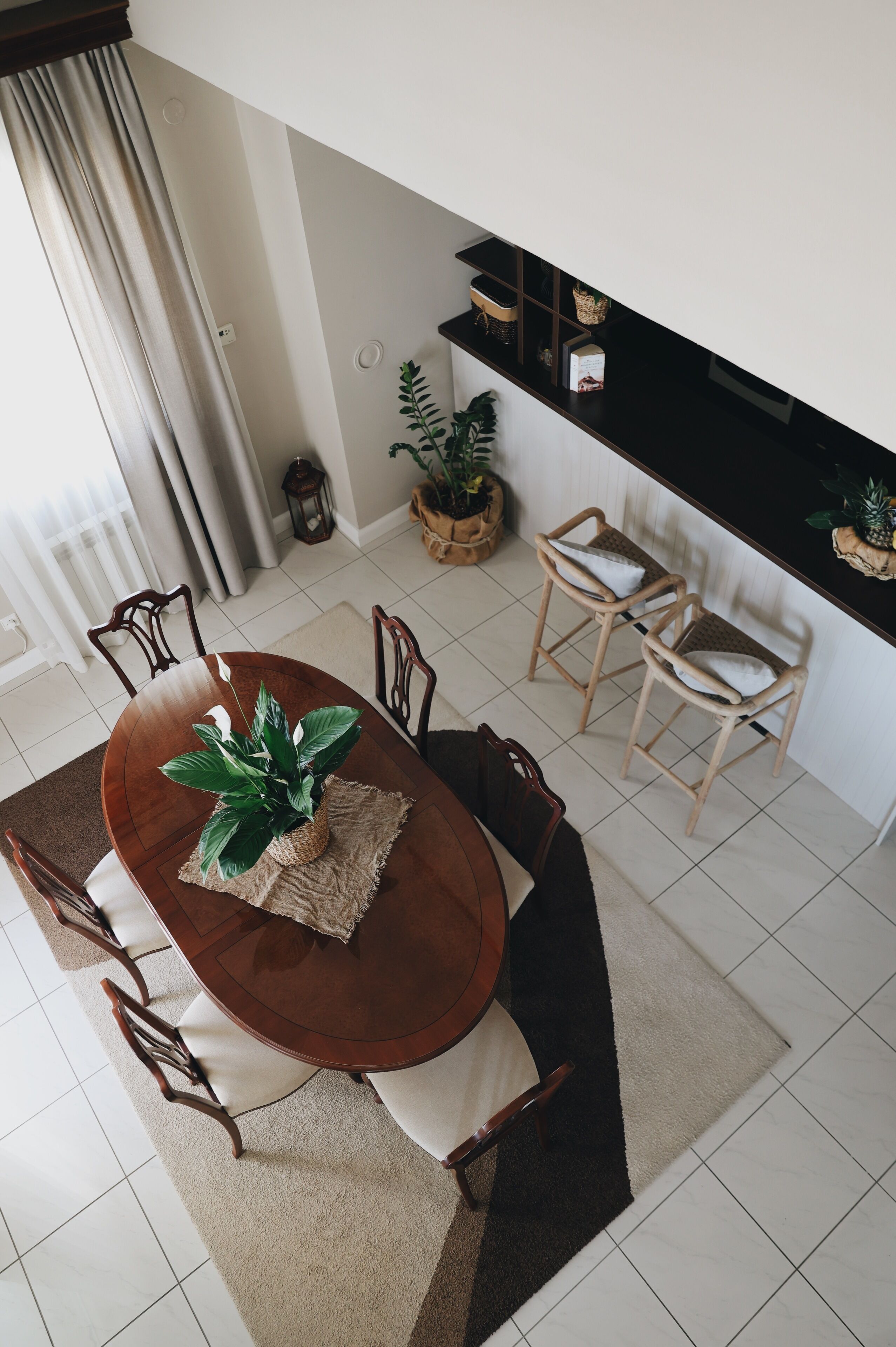 A dining area with a wooden table and chairs, a potted plant, and a kitchen counter with shelves.