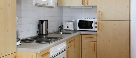 Una cocina con armarios de madera, estufa, microondas y tostadora.