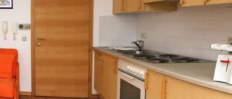 A kitchen with wooden cabinets, a stove, and a sink.