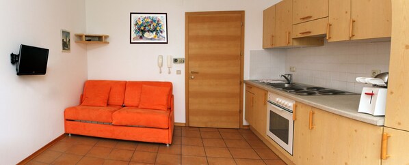 A compact kitchen with a stove, oven, and a small dining area. - Appartment Mühlrast (Laces)