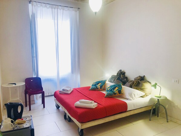 Ein Hotelzimmer mit Bett, Sessel, kleinem Tisch und Lampe.