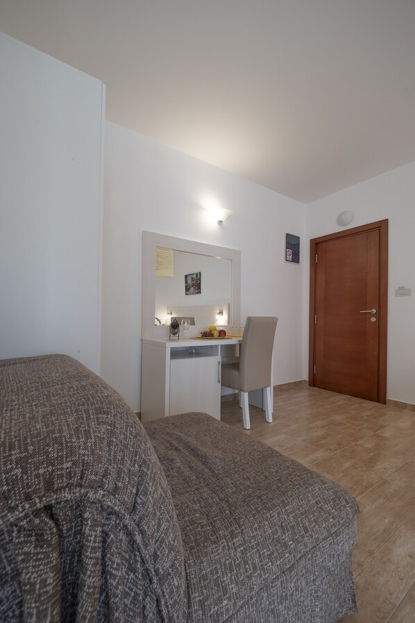 A bedroom with a bed, a desk, a chair, and a door. - Villa Skyprime (Budva)