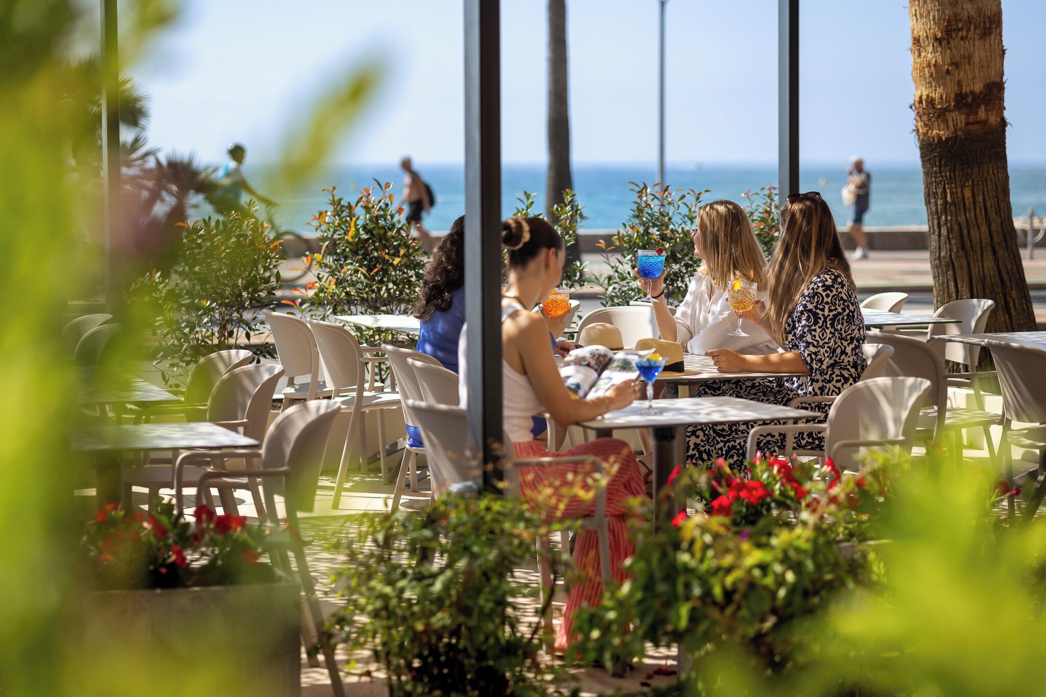 Un espacio de comedor al aire libre con mesas y sillas, con vistas a la playa.
