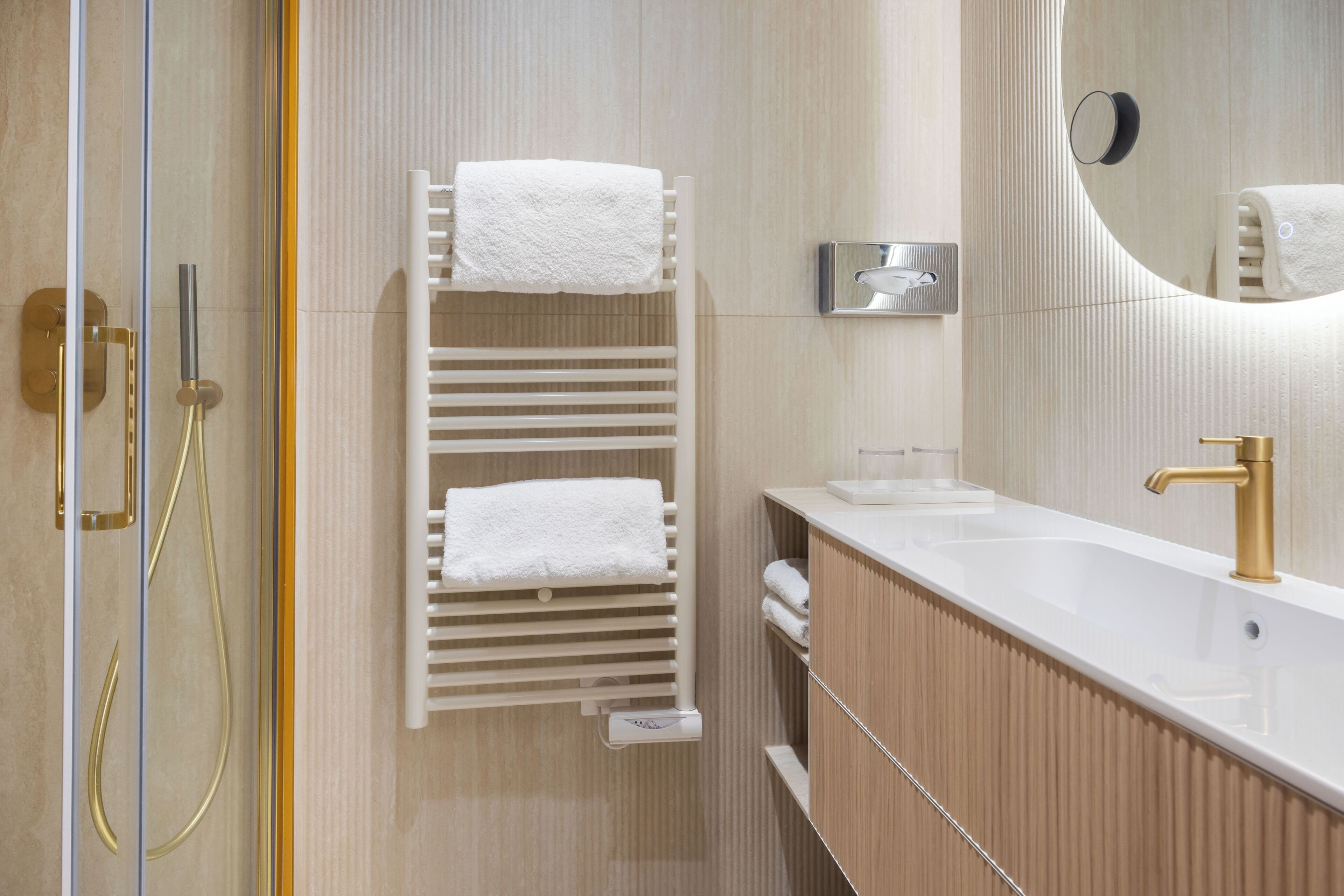 A modern bathroom with a white towel rack, a sink with a gold faucet, and a mirror.