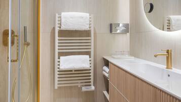 A modern bathroom with a white towel rack, a sink with a gold faucet, and a mirror.