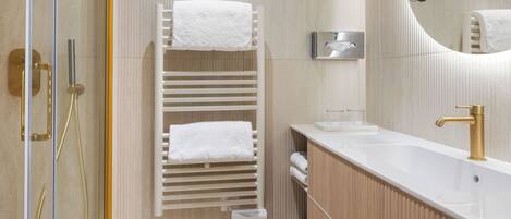 Un baño moderno con un toallero blanco, un lavabo con grifo dorado y un espejo.