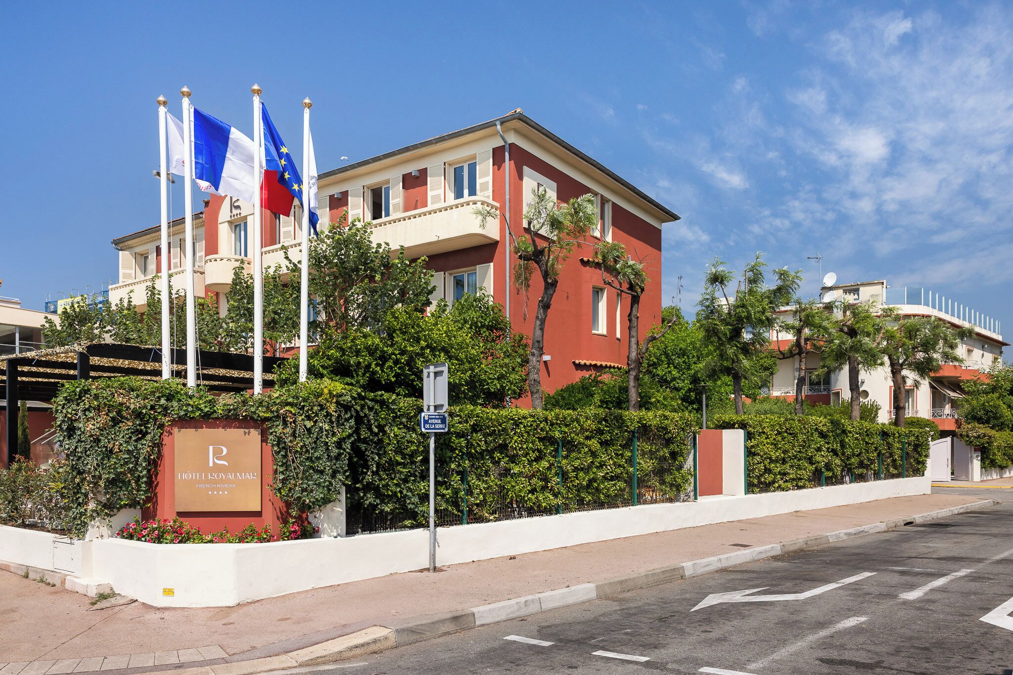 A hotel with a red facade, multiple flags, and a sign indicating it is a Royal.