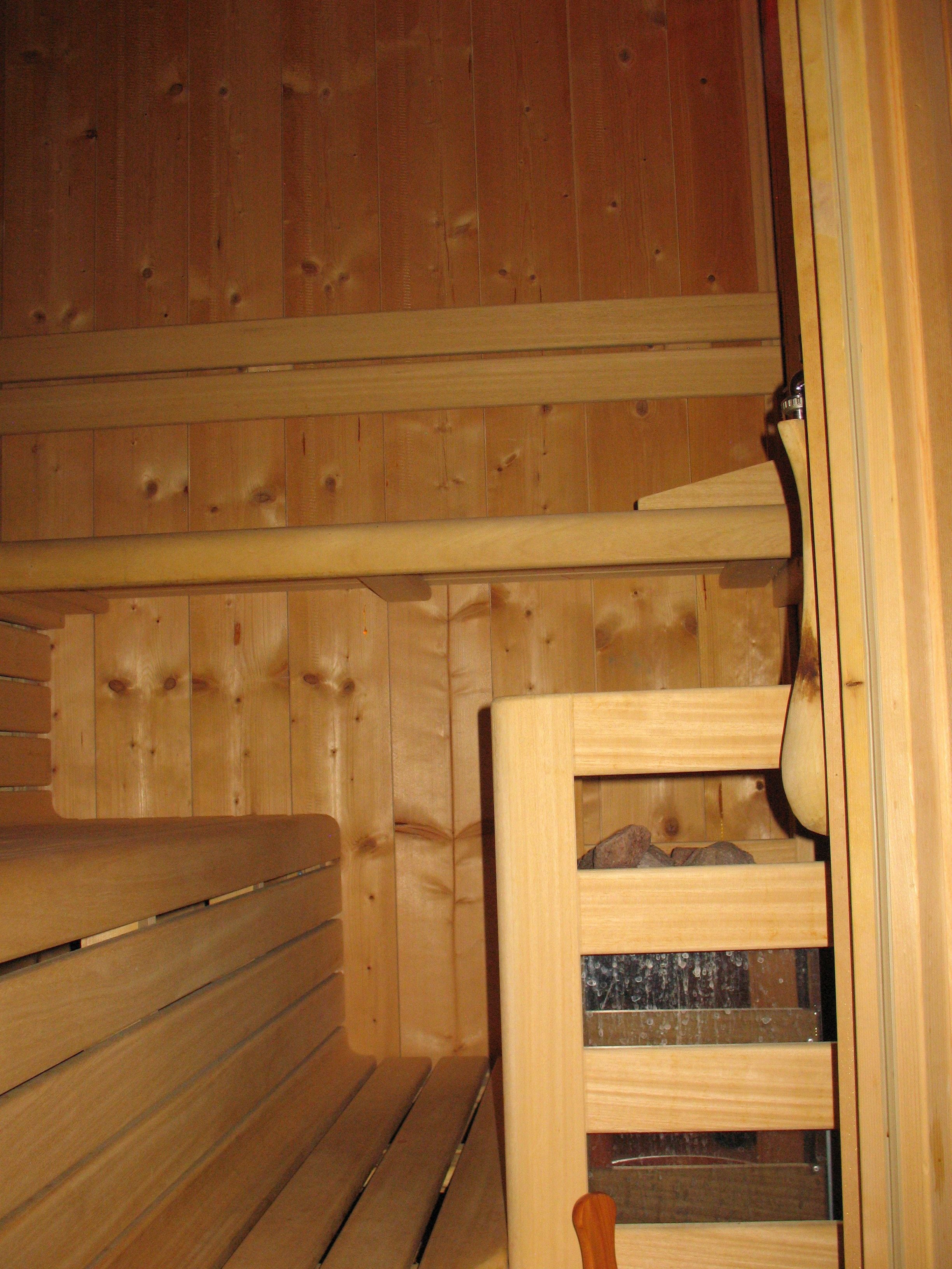 A wooden cabin interior with a bench and a wooden cabinet with a glass door.