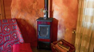 A cozy room with a wood-burning stove, a patterned sofa, and a wooden chest.