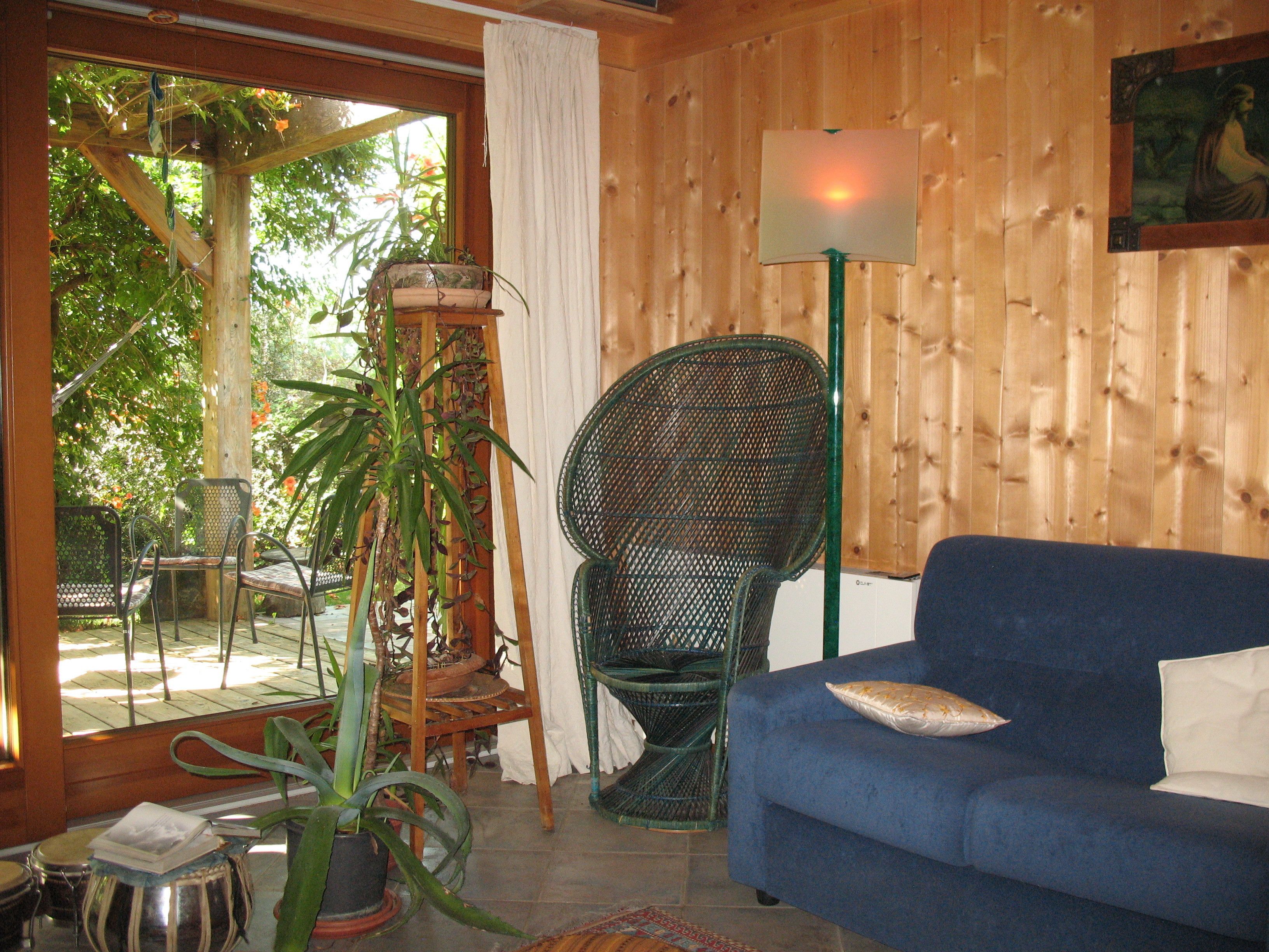 A room with a blue sofa, a wicker chair, a wooden table, and a potted plant.