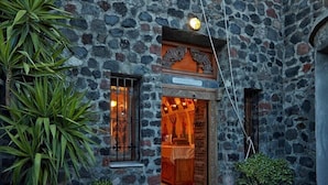 Un edificio de piedra con un campanario, una puerta de madera y plantas en macetas.