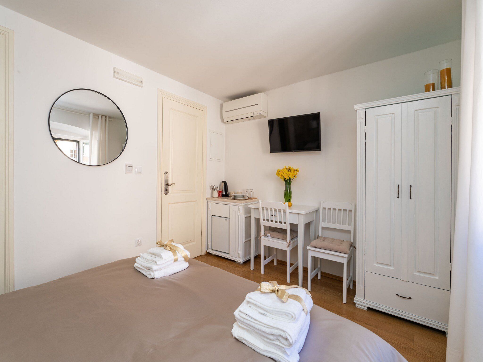 Habitación de hotel con cama, escritorio con sillas, televisor y armario.