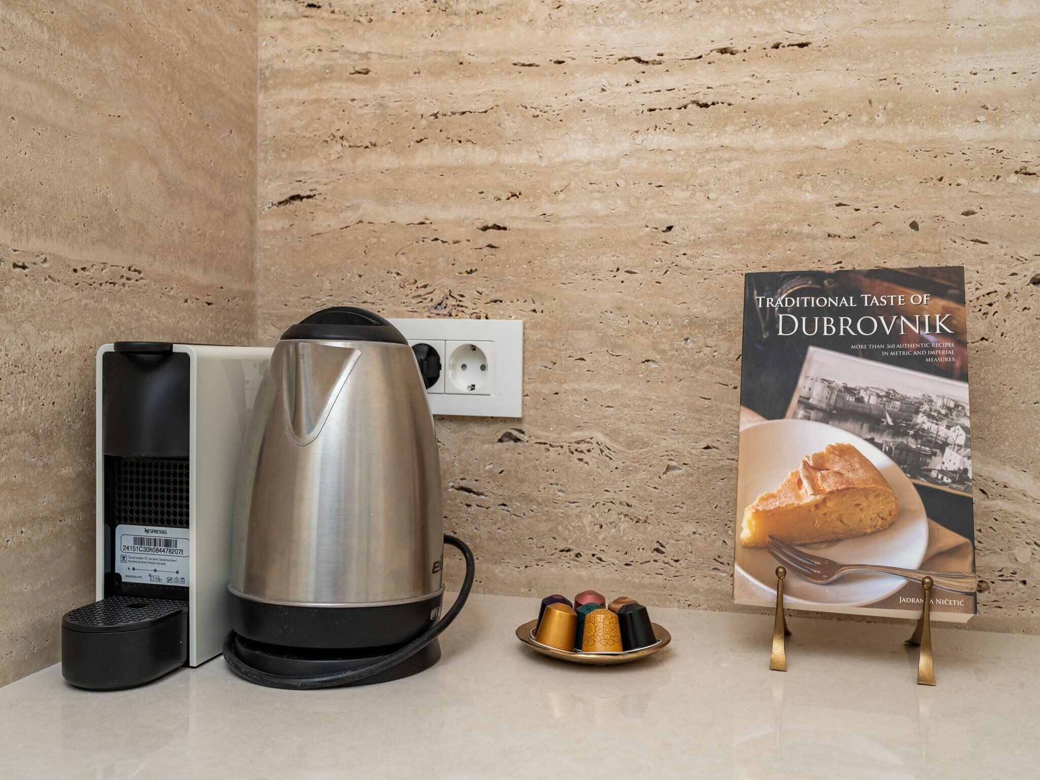 A kitchen area with a coffee maker, a kettle, and a book titled "Traditional Taste of Dubrovnik".