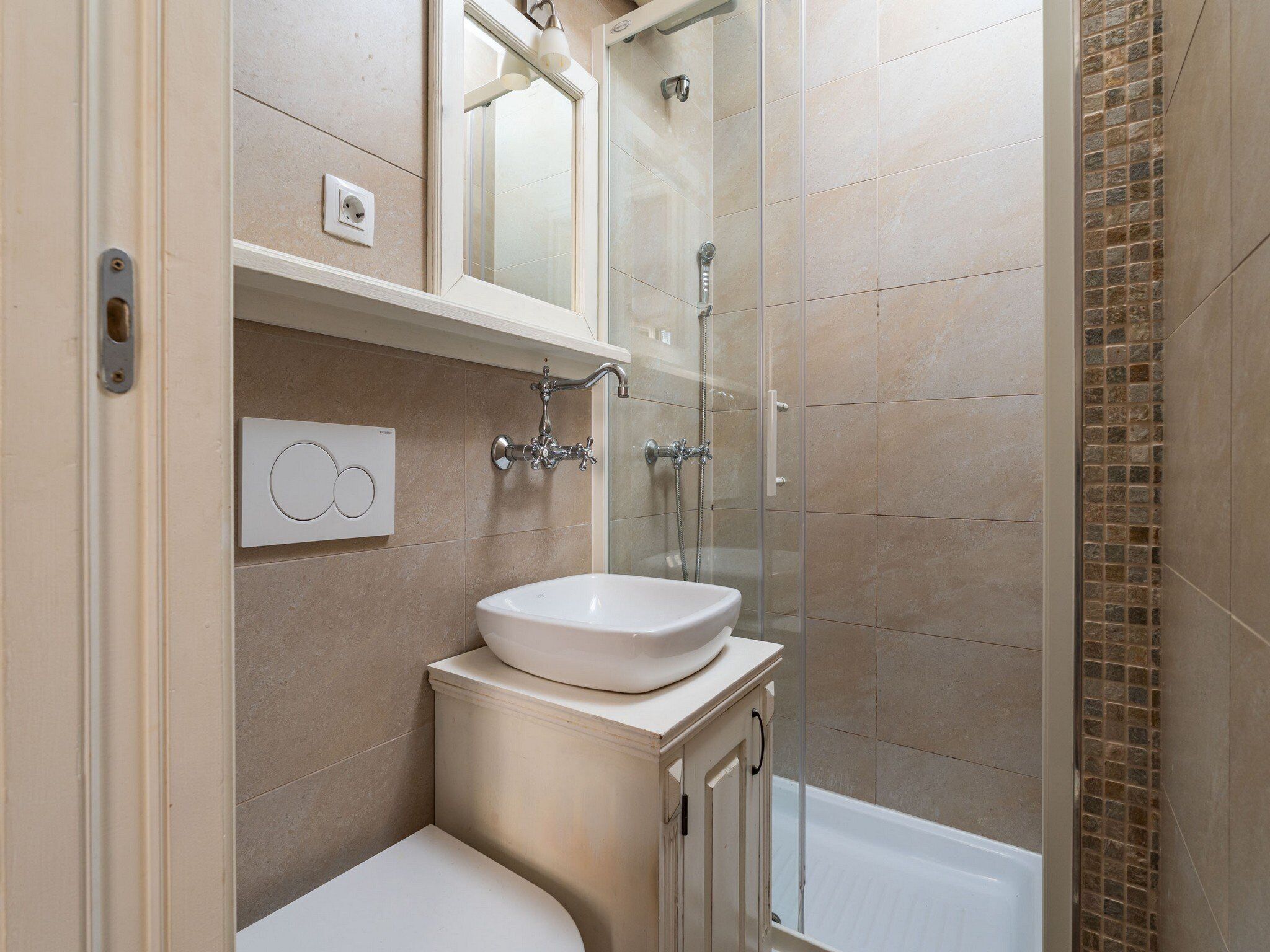 Un baño moderno con ducha cubierta por vidrio, un lavabo blanco y un inodoro.