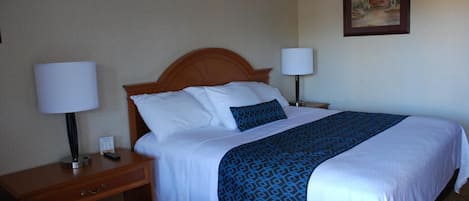 Een hotelkamer met een bed, twee bedlampen, een nachtkastje, een stoel en een schilderij aan de muur.