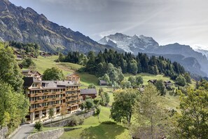 Eine Berglodge mit mehreren Etagen, umgeben von üppiger Vegetation und schneebedeckten Gipfeln.