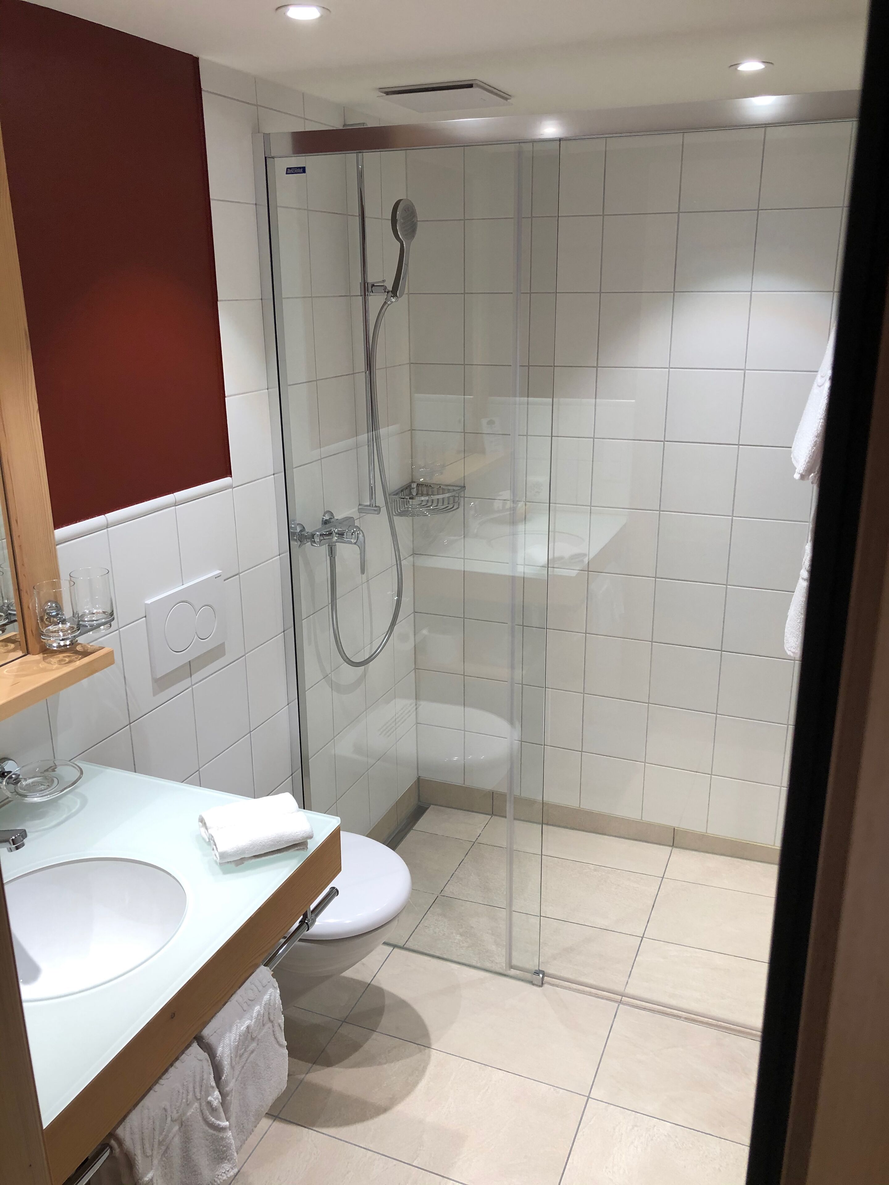 Une salle de bain moderne avec une douche à parois de verre, un lavabo blanc et des toilettes.