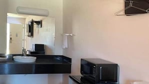 Una kitchenette compacta con microondas, lavamanos y refrigerador pequeño.