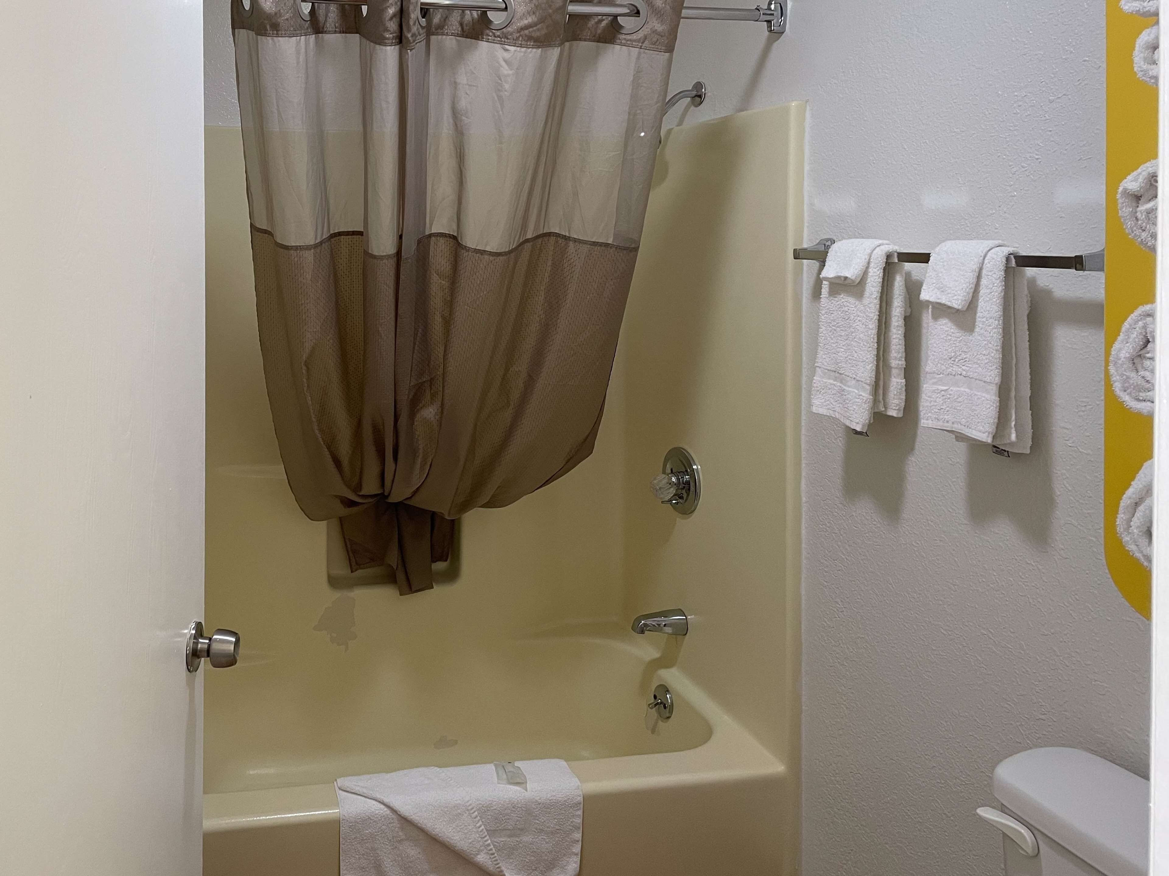 A bathroom with a bathtub, a toilet, and a towel rack with multiple towels.