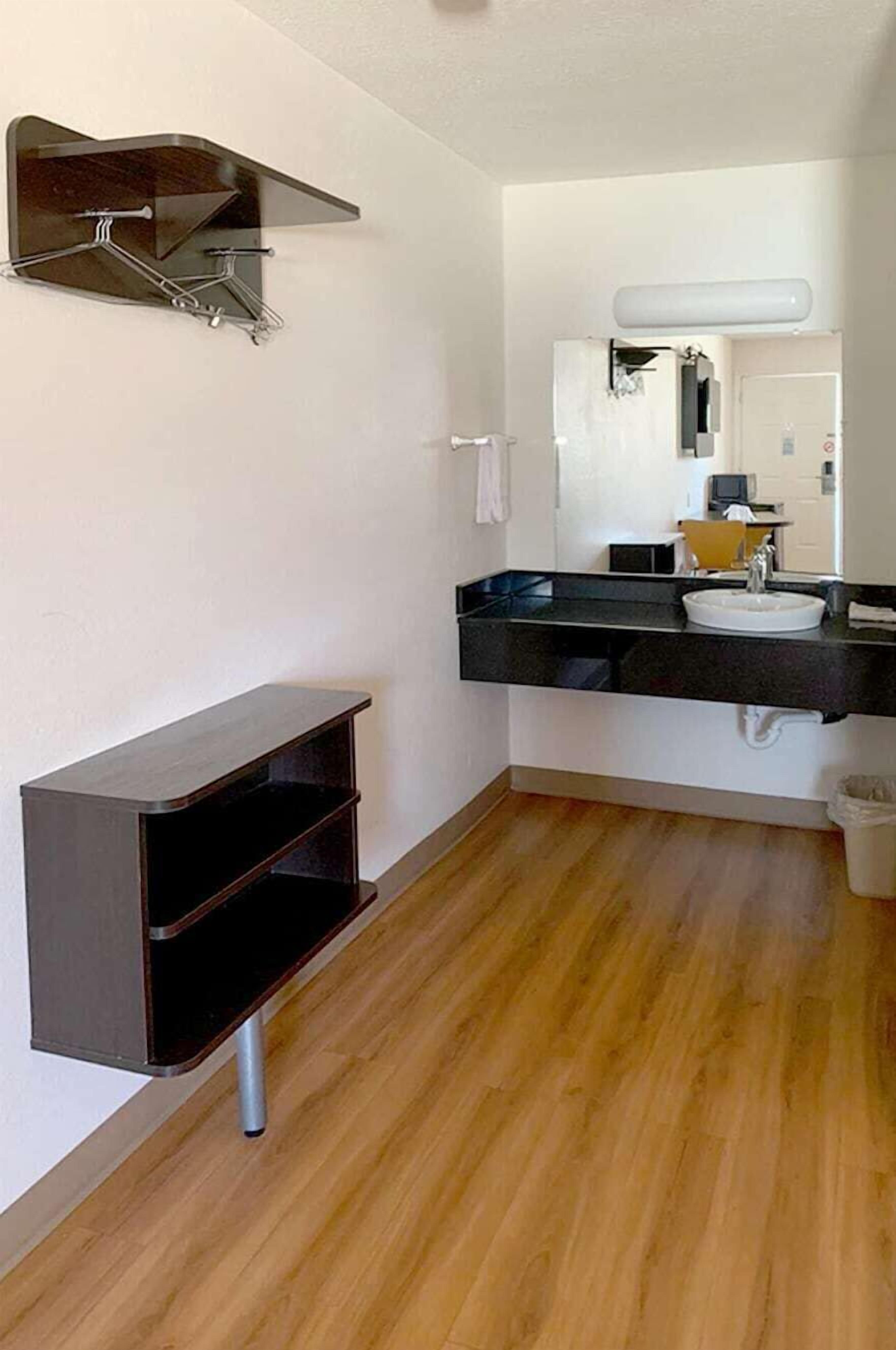 Un baño moderno con un tocador negro, un lavabo blanco y un espejo.
