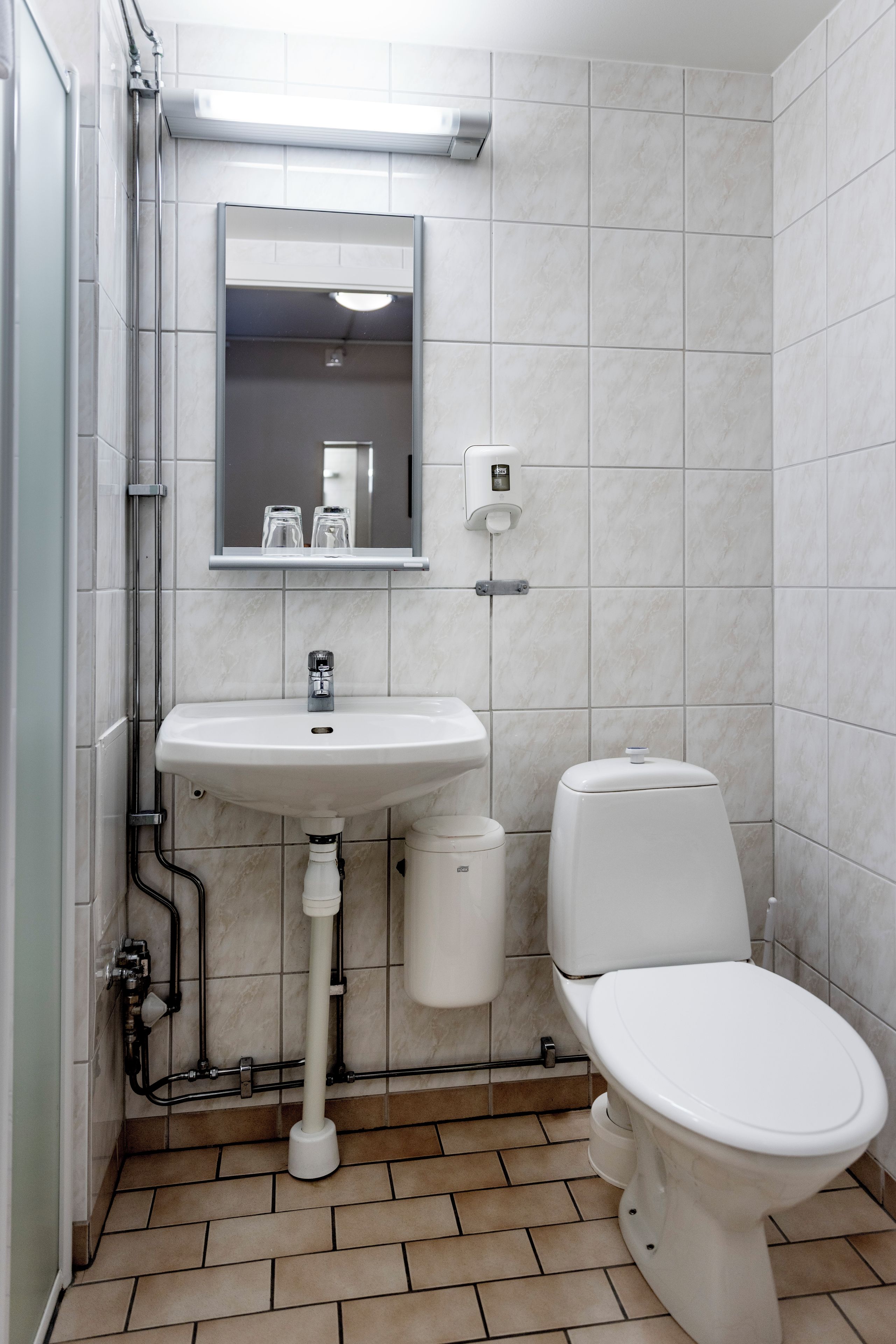 Ein Badezimmer mit weißem Waschbecken, Spiegel und Toilette.