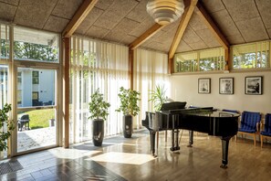 Una habitación amplia con un piano de cola, ventanas grandes y vistas al exterior.