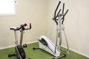 Two stationary bikes in a room with green carpet and white walls. - Wendelsberg STF Hotell (Mölnlycke)