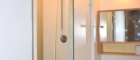 Une salle de bain avec une douche, un lavabo et un miroir.