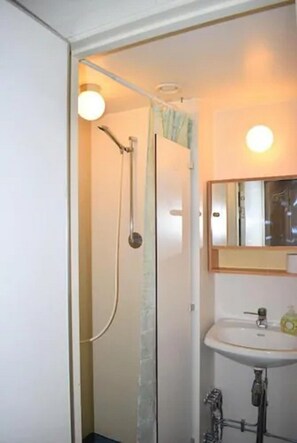 A bathroom with a shower, a sink, and a mirror. - Wendelsberg STF Hotell (Mölnlycke)