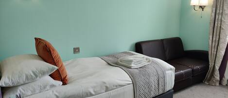 A bedroom with a bed, a sofa, and two wall-mounted lamps.