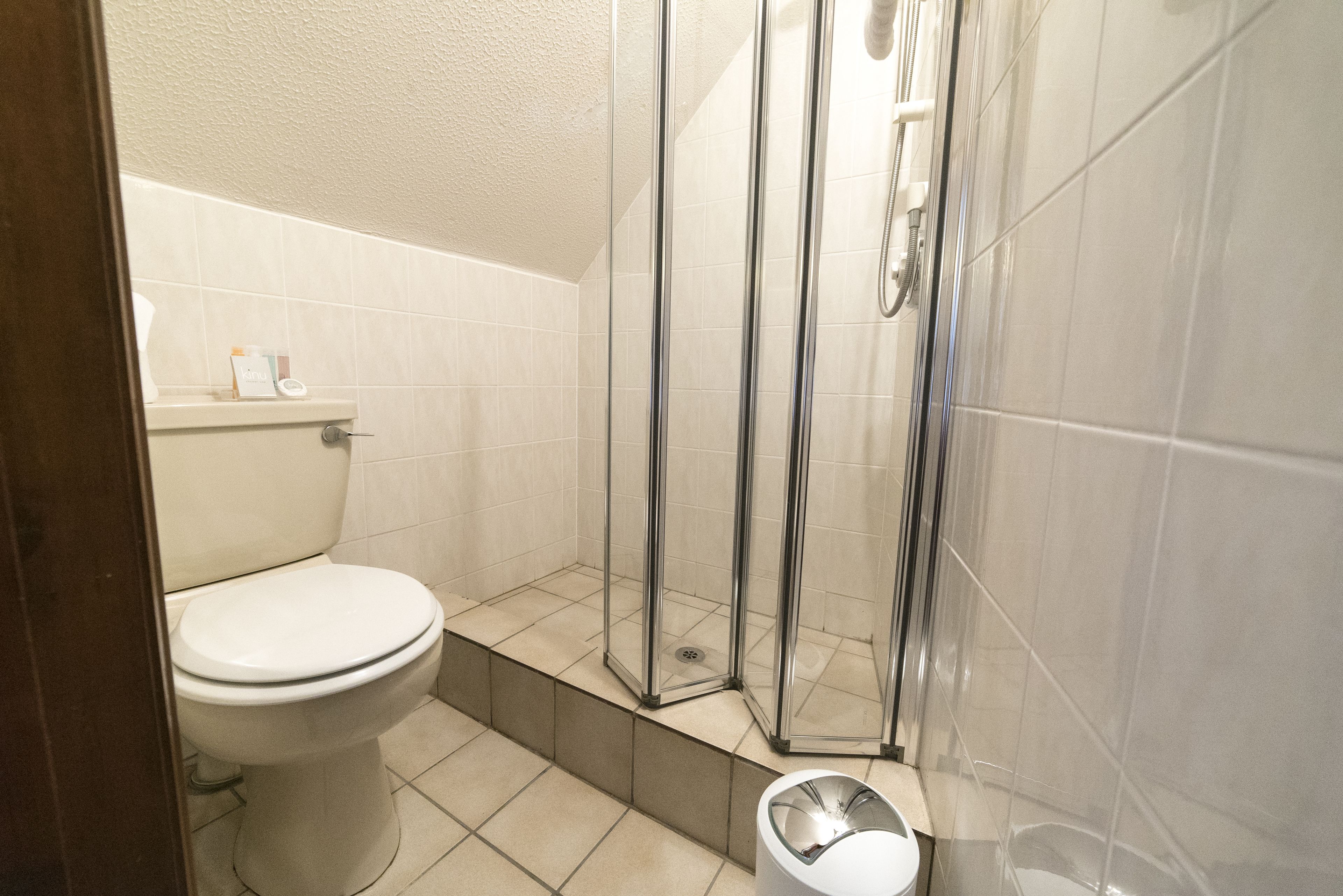 A bathroom with a toilet, a shower with glass doors, and a sink with a mirror.