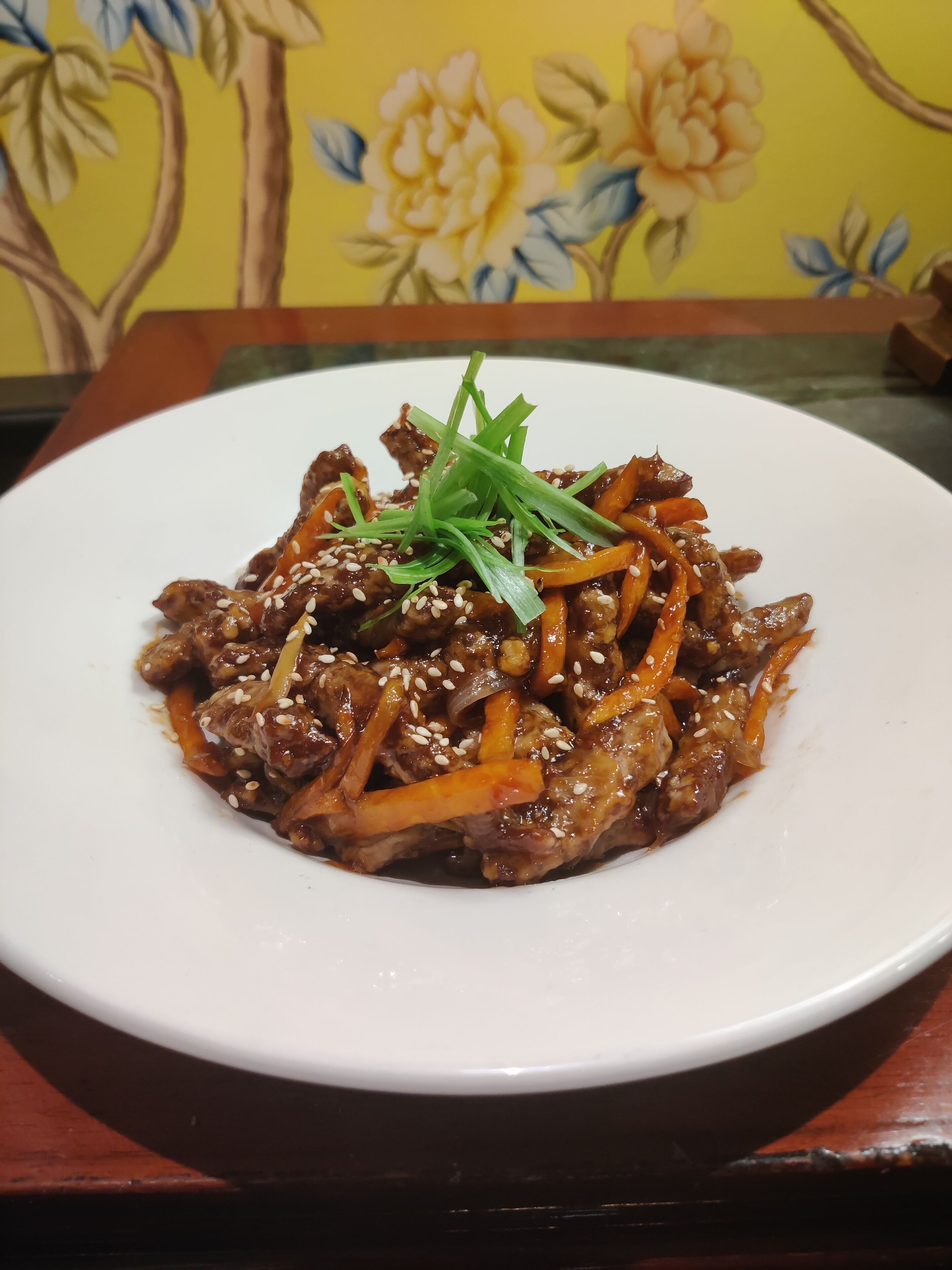 A plate of stir-fried meat with vegetables on a white plate.