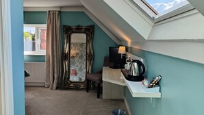 A small, cozy room with a sloped ceiling and skylight, featuring a large ornate mirror, a television, a kettle, and a small shelf with items. - The Bingham Townhouse (Nottingham)