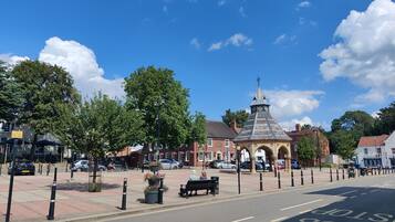 A street with a bus stop and a historic building with a clock tower.