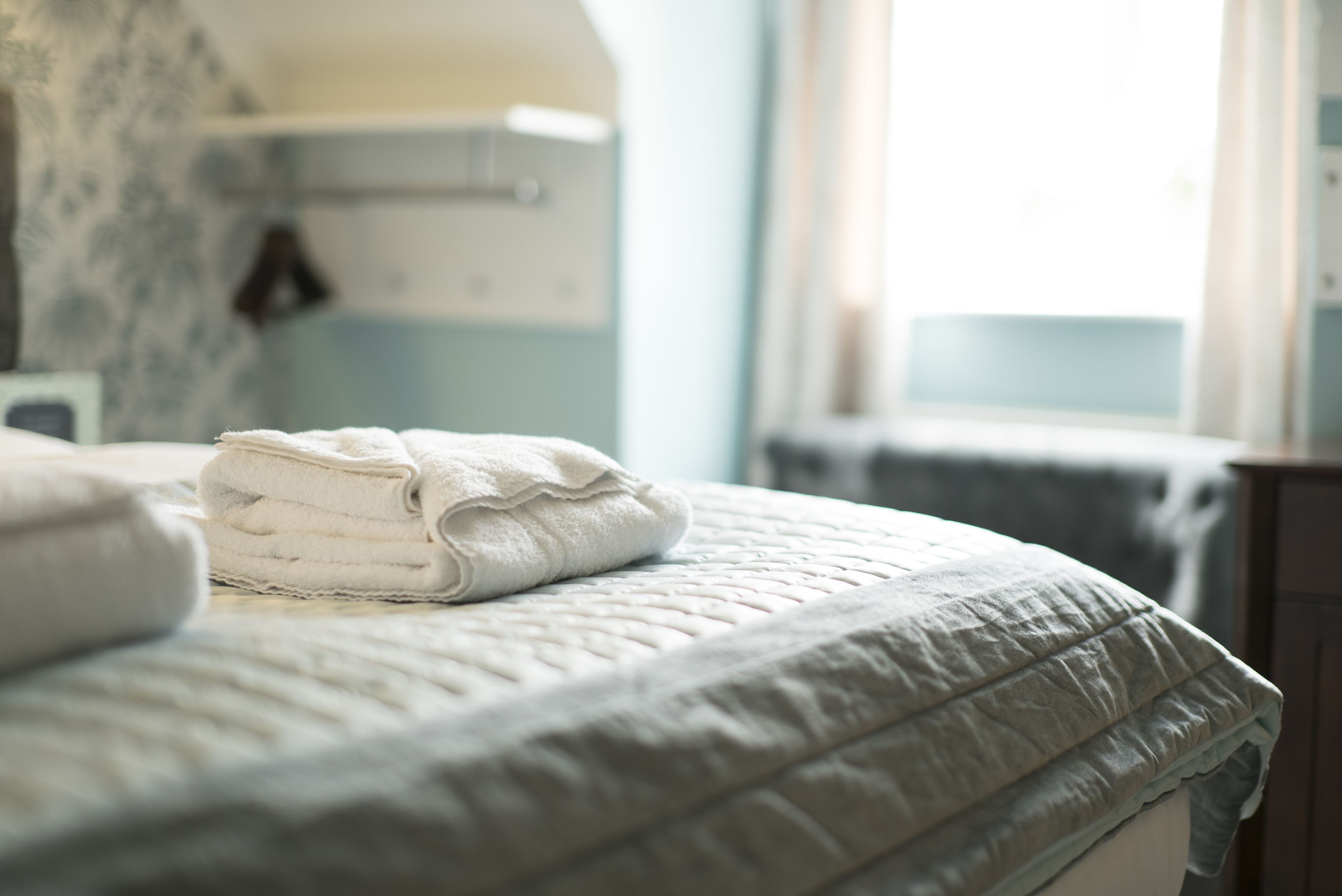 A neatly made bed with a folded white towel and a quilted blanket.