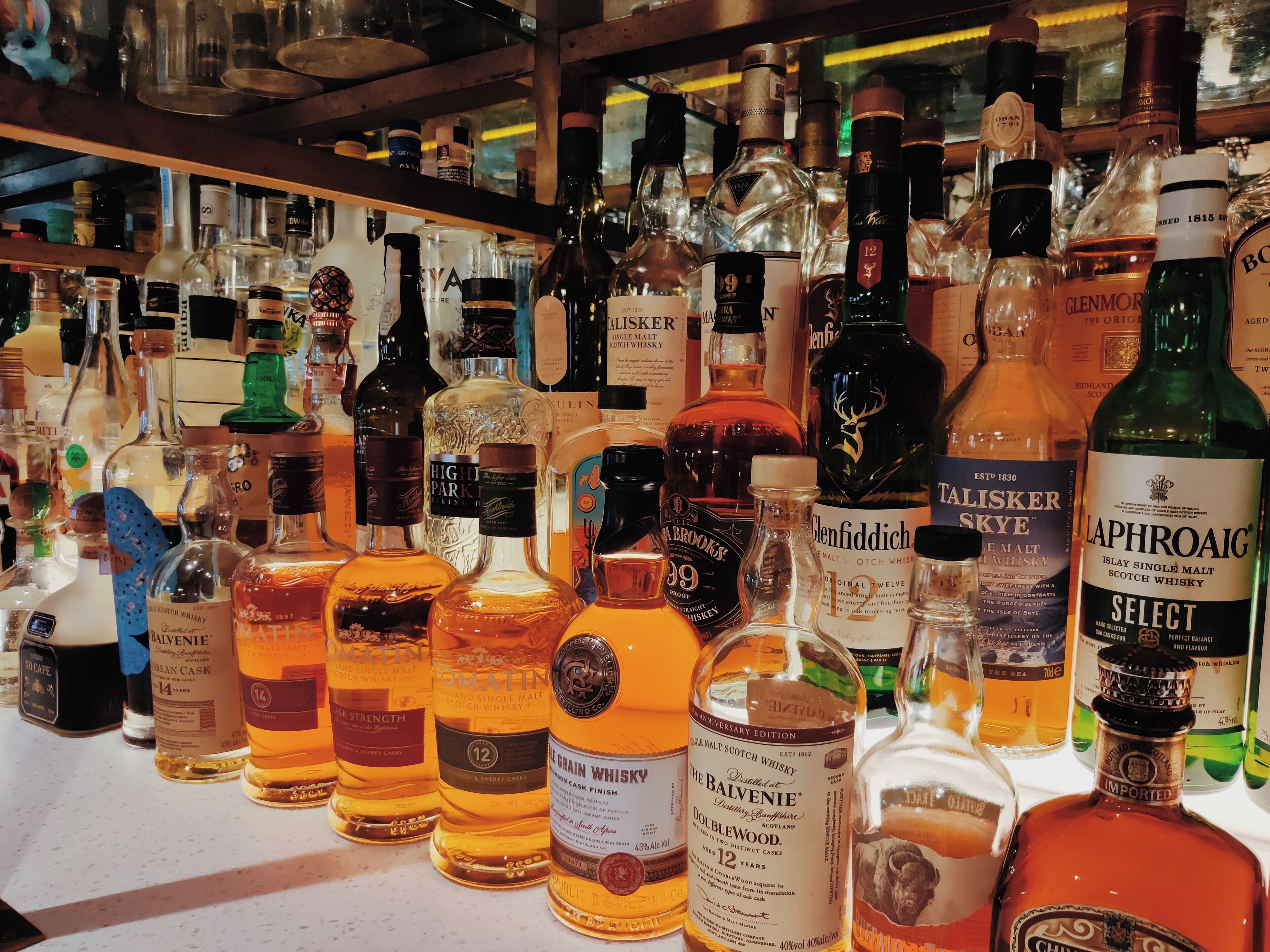 Verschillende flessen whisky staan uitgestald op planken.