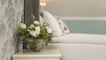 Relax in a serene bedroom with a stylish bed, bedside table, and elegant floral wallpaper.